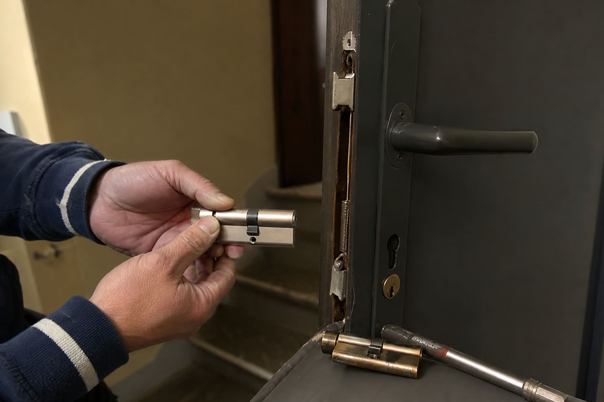 mains insérant un nouveau cylindre dans la porte